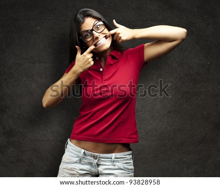 portrait of a happy young woman gesturing with her mouth against a grunge wall