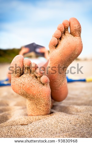 Woman reading a book on the beach. Shallow deep of focus.