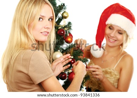 Two girlfriends in santa hat and near Christmas tree on a white background.