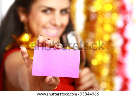 Friendly girl showing blank business card isolated on christmas decorated background. Focus on card