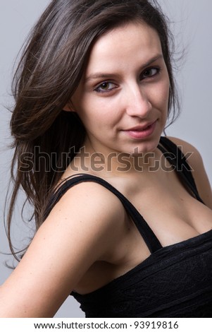 Closeup portrait of a beautiful young woman smiling, against a grey background
