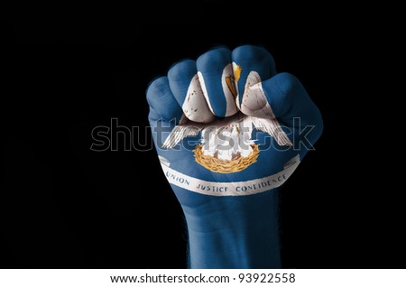 Low key picture of a fist painted in colors of american state flag of louisiana