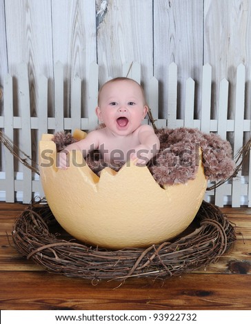 sweet baby happily sitting in giant egg