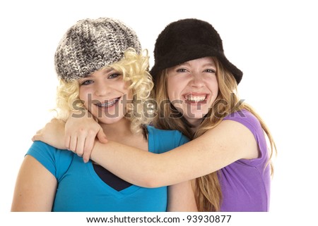Two teen girls with funny hats and a wig on with smiles on their faces.