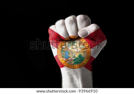 Low key picture of a fist painted in colors of american state flag of florida