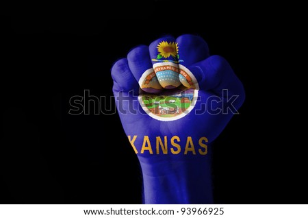 Low key picture of a fist painted in colors of american state flag of kansas