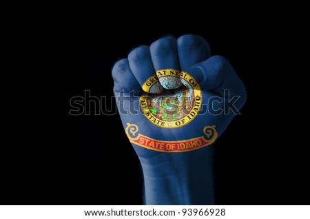 Low key picture of a fist painted in colors of american state flag of idaho