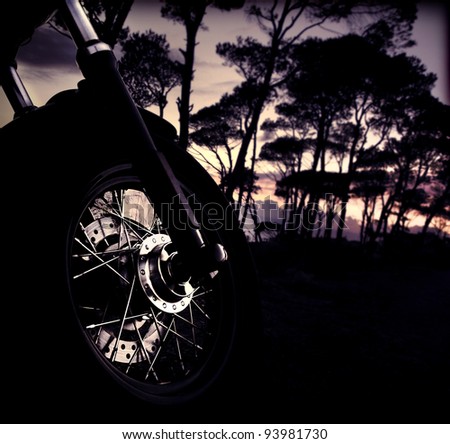 Motorbike wheel over forest sunset, selective focus on part of bike, shiny tire details, outdoor adventure ride, summer fun trip, freedom lifestyle concept