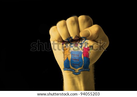 Low key picture of a fist painted in colors of american state flag of new jersey