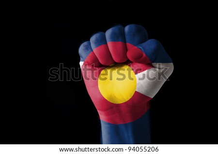 Low key picture of a fist painted in colors of american state flag of colorado
