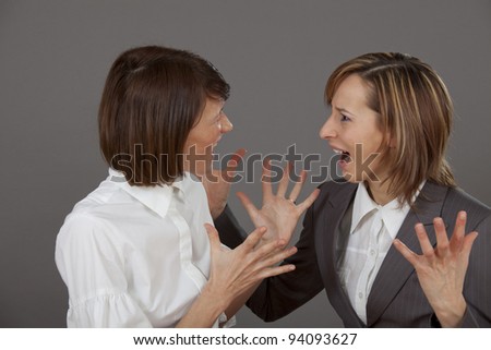 two business women in dispute over grey background