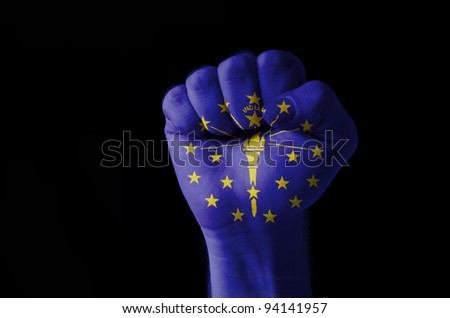 Low key picture of a fist painted in colors of american state flag of indiana