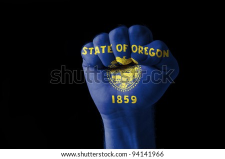Low key picture of a fist painted in colors of american state flag of oregon