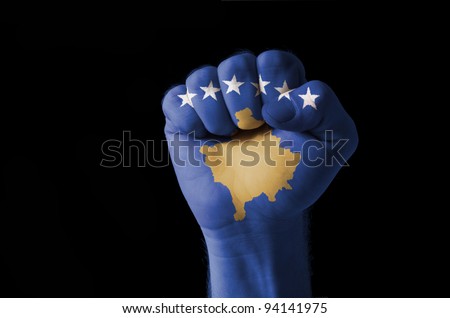 Low key picture of a fist painted in colors of kosovo flag
