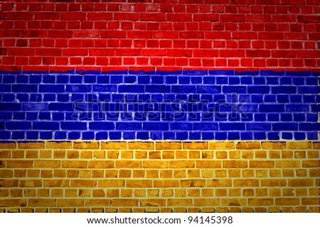 An image of the Armenian flag painted on a brick wall in an urban location