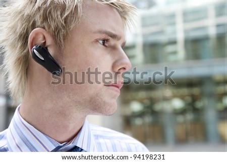 Young businessman using a hands free device to speak on the phone, in the financial district.