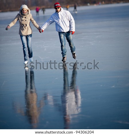 Couple ice skating outdoors on a pond on a lovely sunny winter day