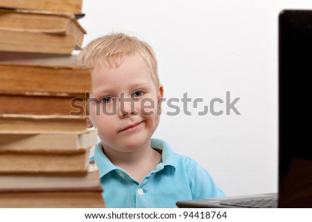 Cheerful smiling  little boy sitting at the table. Looking at camera. School concept