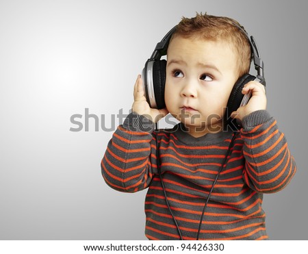 portrait of a handsome kid listening to music looking up over grey background