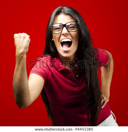 portrait of young woman gesturing victory against a red background