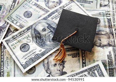mini graduation cap on top of a pile of cash Royalty-Free Stock Photo #94530991