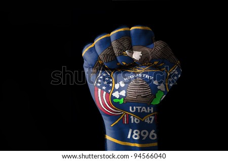 Low key picture of a fist painted in colors of american state flag of utah