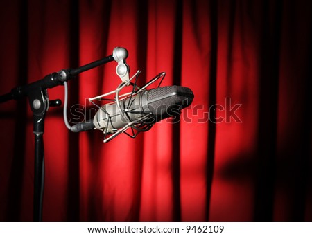 Vintage microphone with spotlight over a red curtain