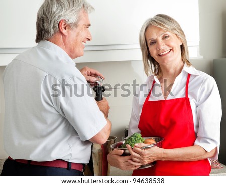 Happy senior couple cooking together in kitchen