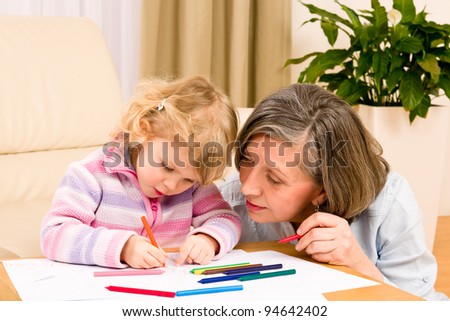 Grandmother and granddaughter drawing together with pencils at home