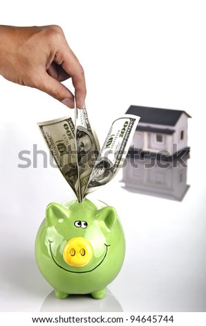 a man's hand putting money into a piggy bank