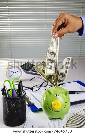 a hand putting money into piggy bank
