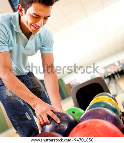Casual man picking up a bowling ball