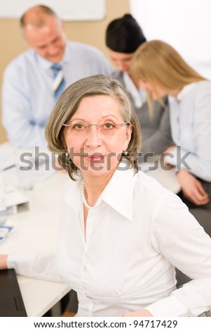 Business team meeting executive senior businesswoman with colleagues in background