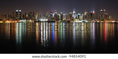 New York City Manhattan midtown skyline panorama at night with lights reflection over Hudson River.