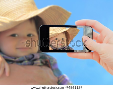 Hand making shot of little boy in cowboy hat