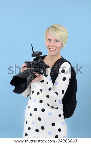photographer with D SLR camera and backpack on blue background