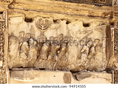 This wall relief on the Arch of Titus reveals Roman soldiers after the destruction of the Temple of Jerusalem in 70 A.D including the Temple Menorah, the Table of the Shewbread and silver trumpets. Royalty-Free Stock Photo #94914505