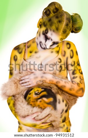 Pregnant woman with body-art as leopard over green background