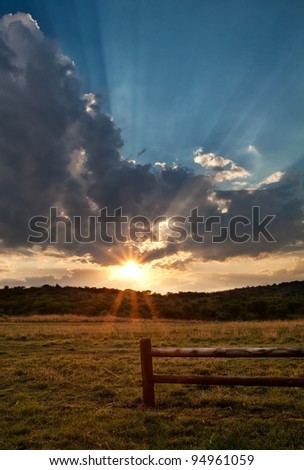 Wooden fence at sunset with the sunbeams prominent in the picture
