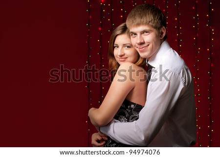 couple embracing against the backdrop of multicolored lights in studio