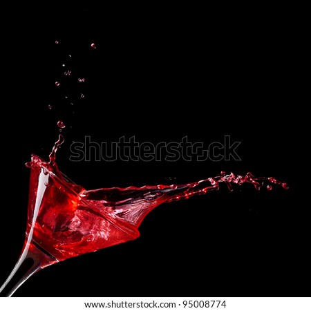 red martini cocktail splashing into glass on black background