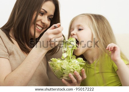 little girl eats vegetarian meal with young mother