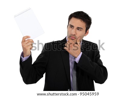 Businessman looking at notepad curiously