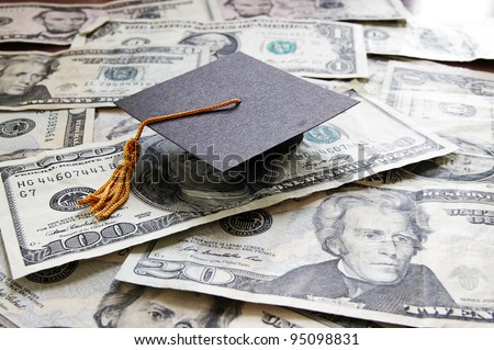 mini college graduation cap on cash Royalty-Free Stock Photo #95098831
