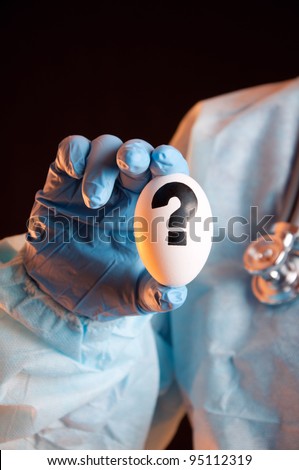 Scientist's hand holding white egg with question mark on it