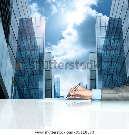 Businessman signing contract against modern offices