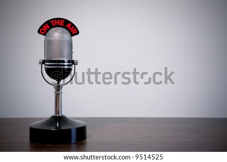 Retro microphone with an 'On the Air' illuminated sign on a desk, vignetted background. Royalty-Free Stock Photo #9514525