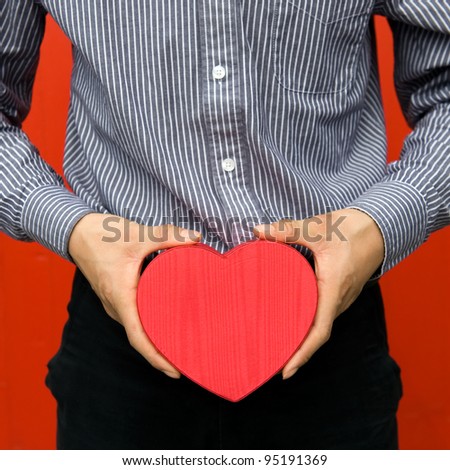Heart shaped gift box in hands.