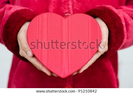 Heart shaped gift box in hands.
