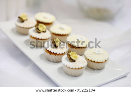 Decorated white vanilla cream cupcakes on a white plate